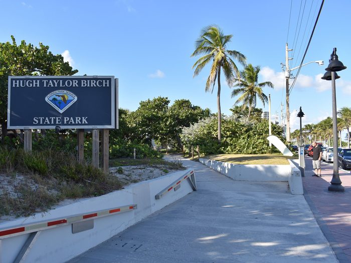 The Hugh Taylor Birch State Park entrance sign under palms at the A1A gate.