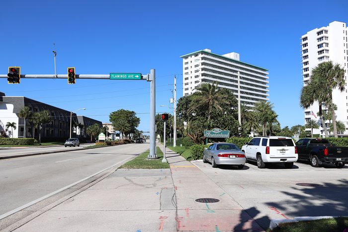 A street corner in Lauderdale-by-the-Sea with low buildings, palms and a crosswalk.