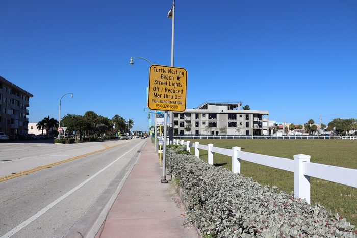 A yellow Turtle Nesting Beach sign on North Ocean Drive in Lauderdale-by-the-Sea asking for street lights off or reduced March through October.